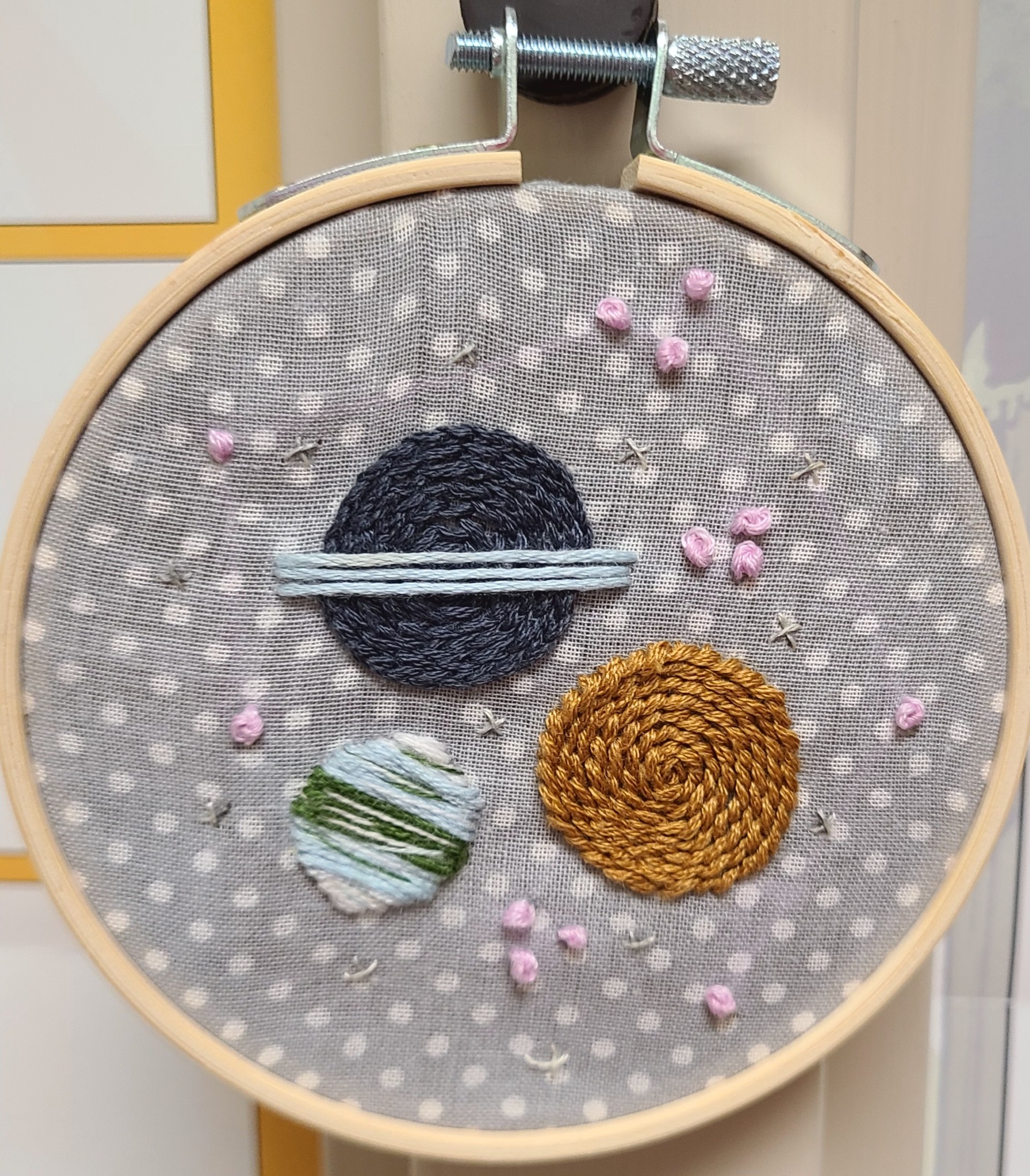 Embroidery hoop with three planets and stars around in the center