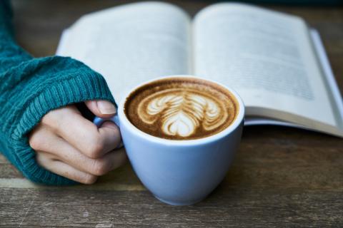 Woman holding a coffee mug reading a book