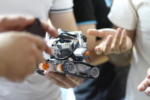 People standing, holding a Lego robot