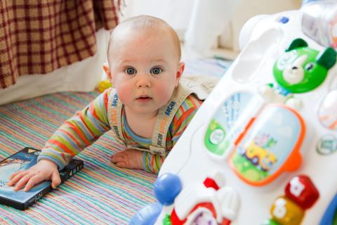 Baby on the floor on its tummy playing with toys