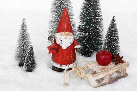 Snow with trees, a Santa, and a wooden sled with a red round ornament on top