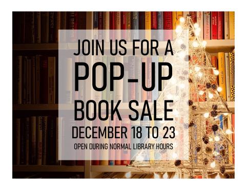 Book shelf in the background with a white light wooden Christmas tree with pinecone ornaments