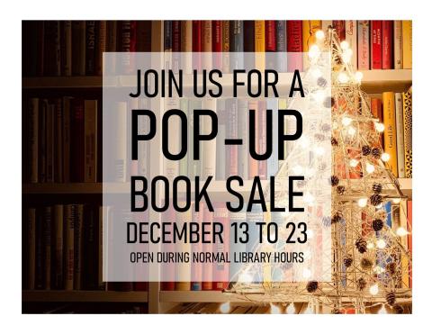 Book shelf in the background with a white light wooden Christmas tree with pinecone ornaments