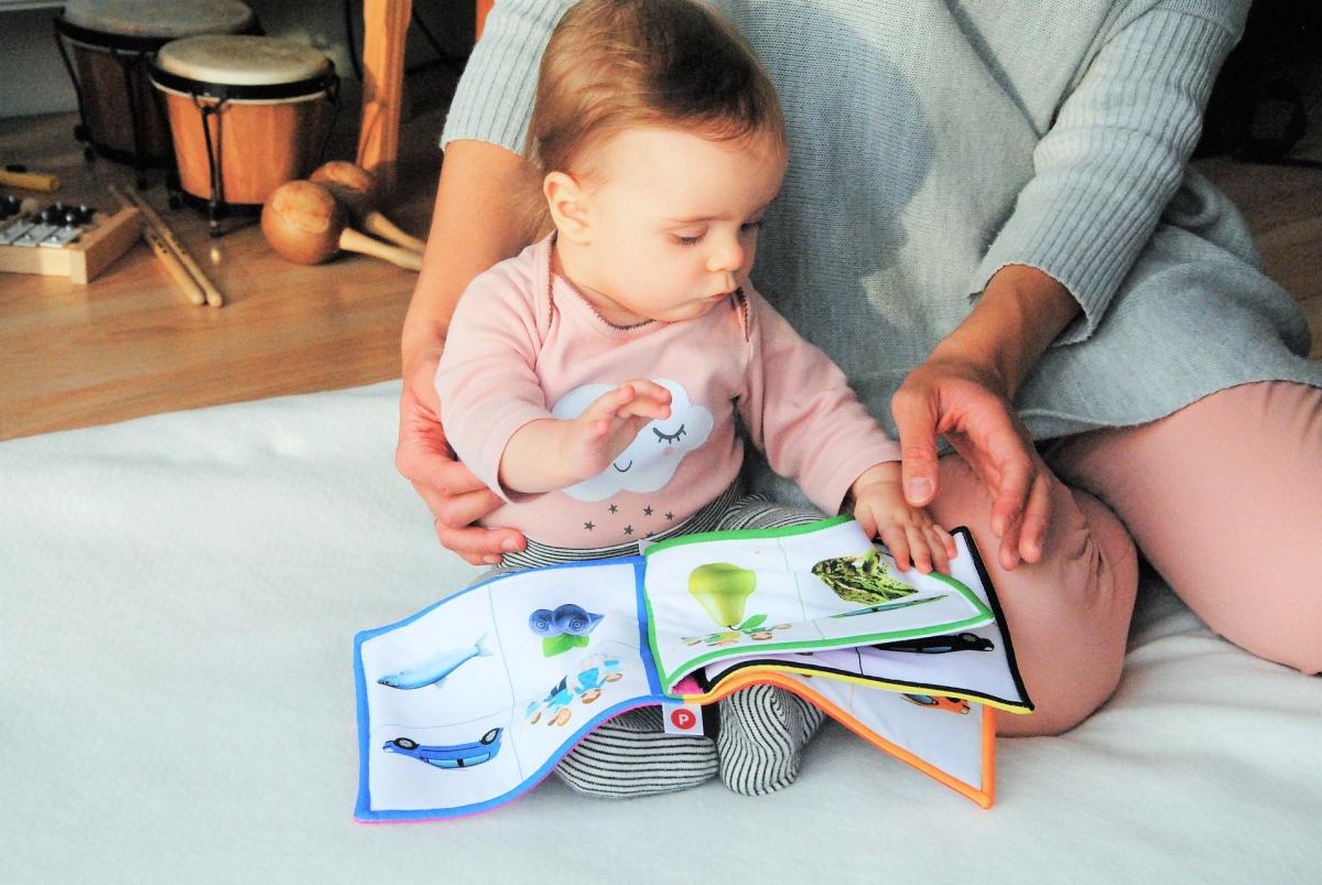 Mother sitting with child reading a book on the floor with music instruments behind them.