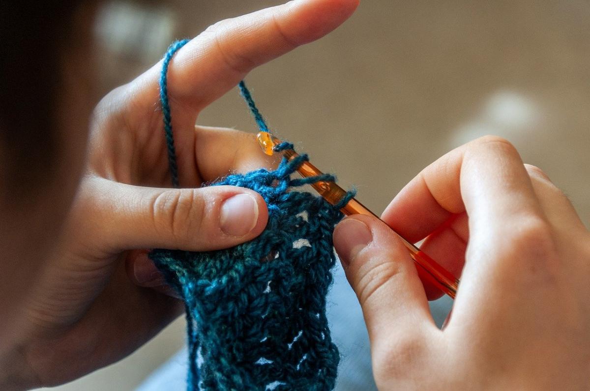 Hands crocheting something that's blue colored