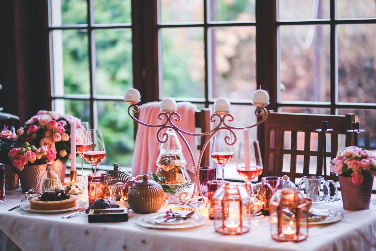 Table with food, wine, candles, candle centerpiece, flowers and Christmas tree